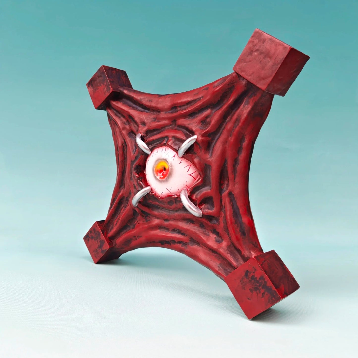Figurine Œil Maudit rouge, œil orange dans tête blanche, cornes grises et bras quadrangulaires.