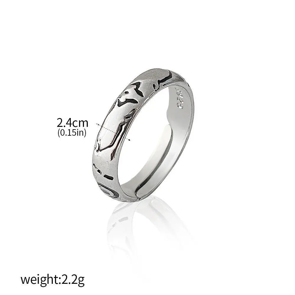 Bague argentée large avec motifs gravés sombres et petites pierres claires.