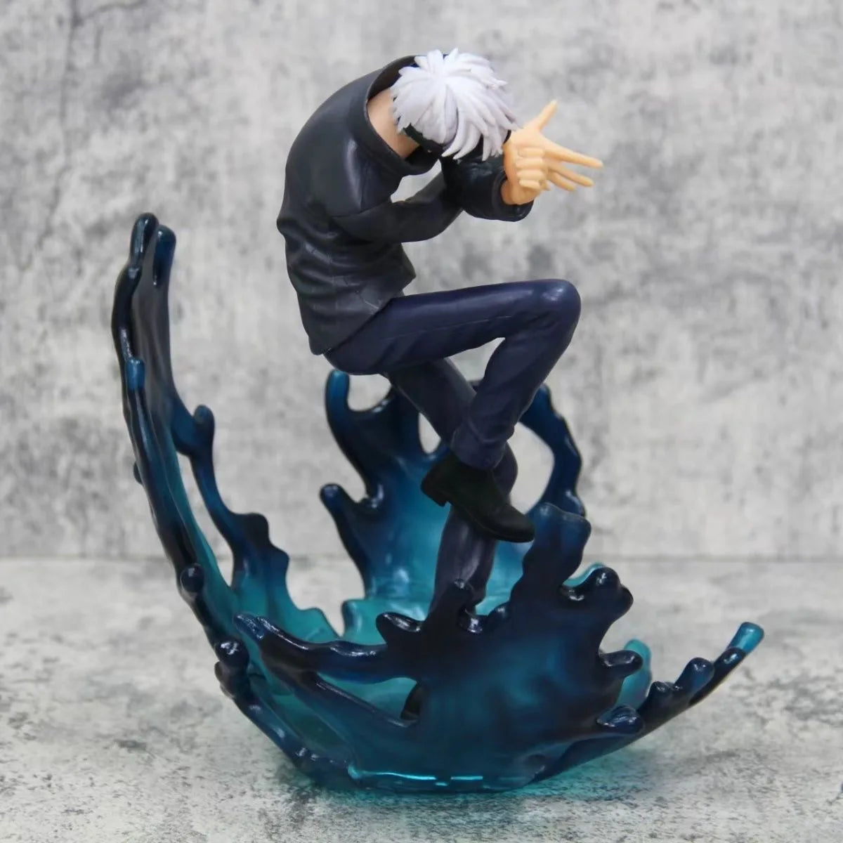 Figurine Jujutsu à genoux, tête tournée, cheveux blancs, tenue noire, base bleue ondulante