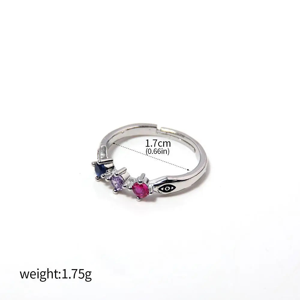 Bague argentée avec pierres bleue, violette et rose, motif gravé sur le côté.