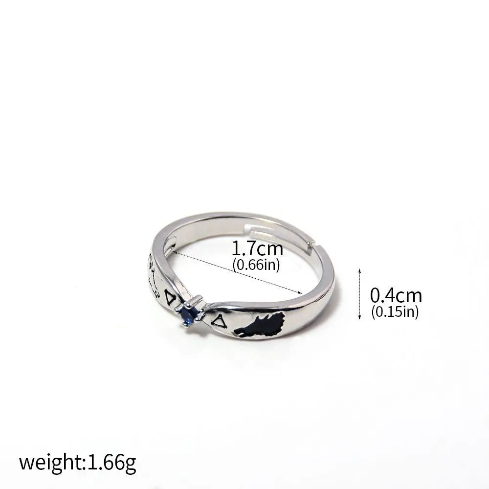 Bague argentée avec motifs gravés et petite pierre bleue sur le côté.