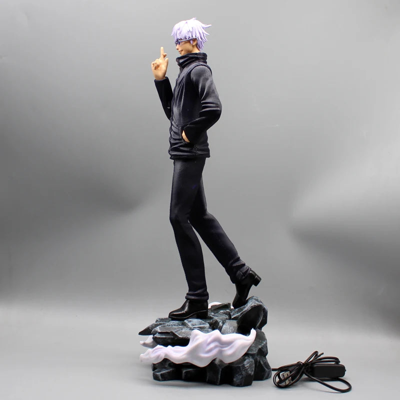 Figurine Gojo Satoru de côté, doigt levé, socle rocheux avec prise et câble.