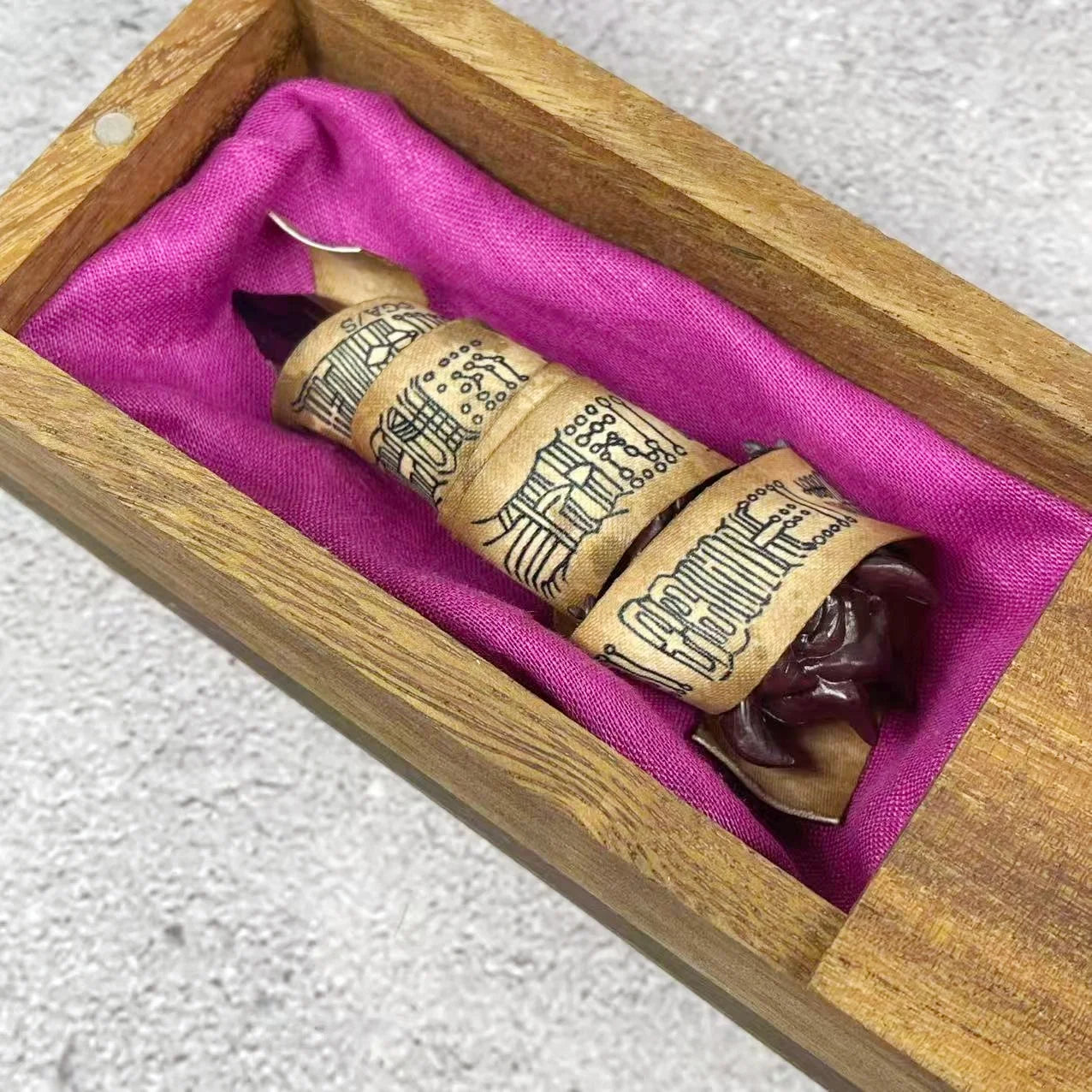 Intérieur de boîte en bois : tissu violet, ruban beige à motifs et doigt sombre