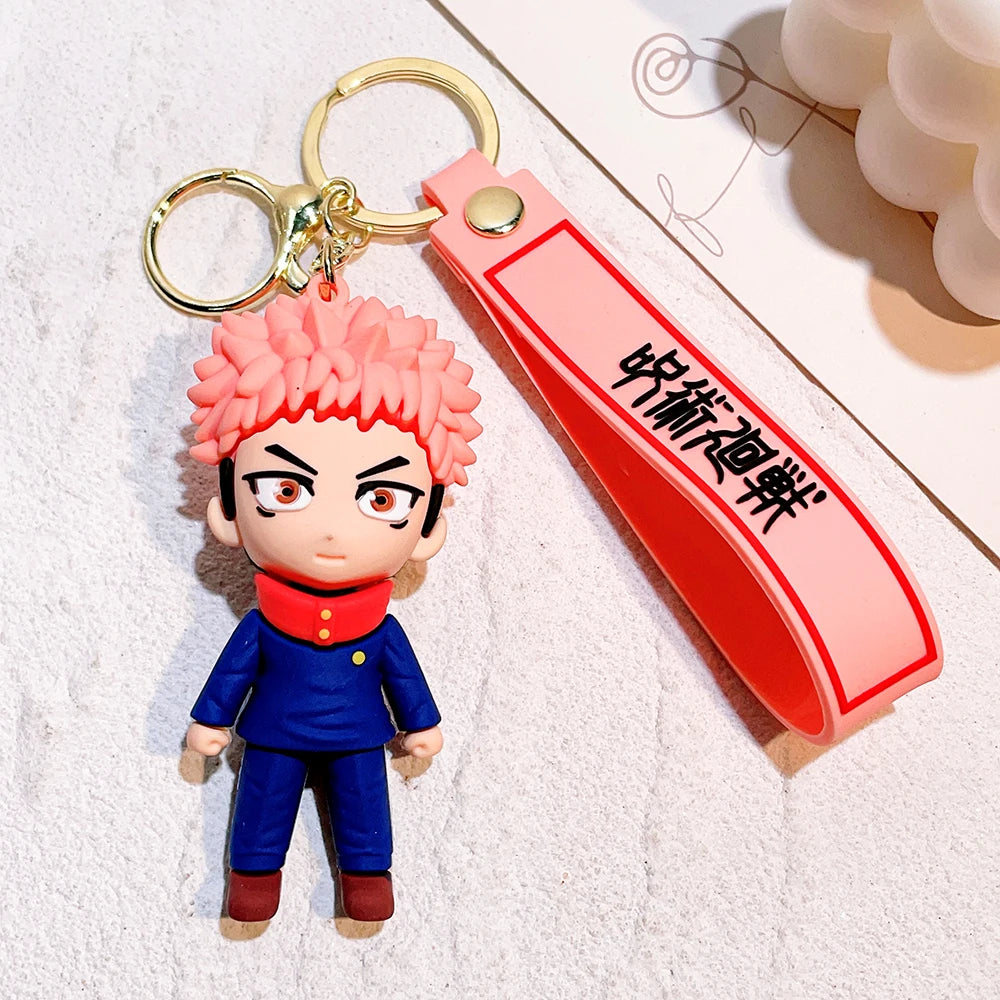 Porte-clé figurine cheveux roses : tenue bleue, lanière rouge avec inscription noire.