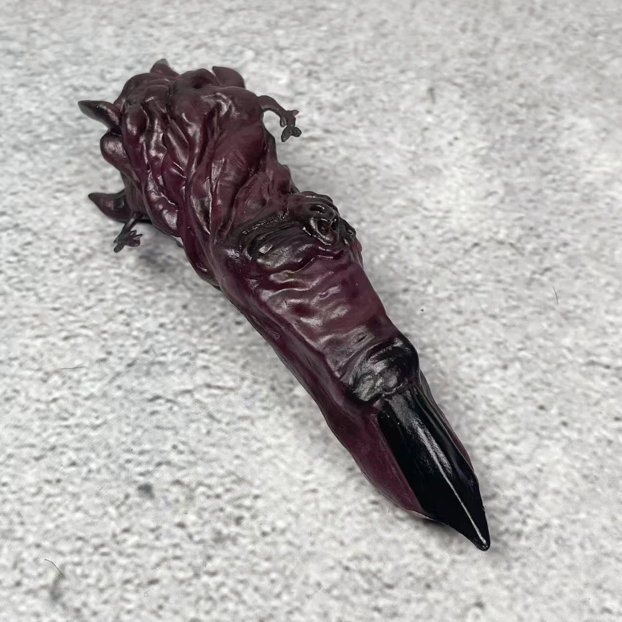 Doigt de figurine en résine sombre, détails sculptés et extrémité pointue