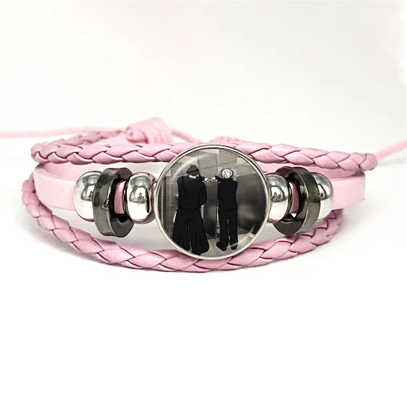 Bracelet à tresse rose avec cabochon rond métal et illustration de deux personnages en silhouette.
