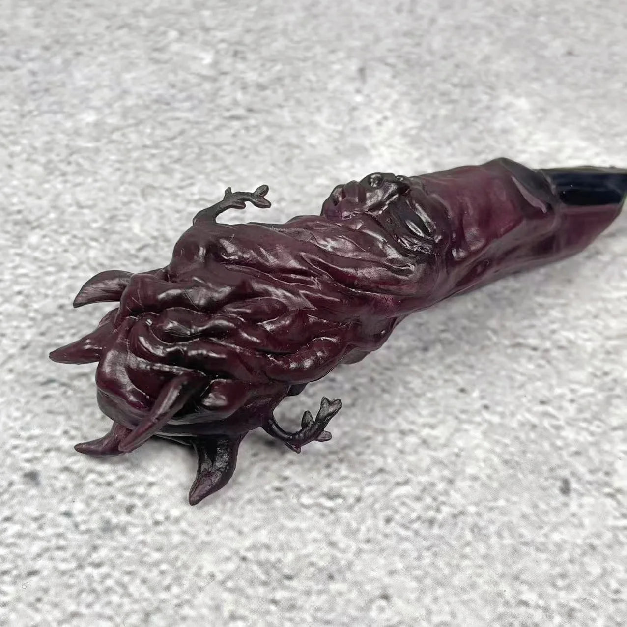 Doigt de figurine en résine sombre aux textures tourbillonnantes, pointe noire