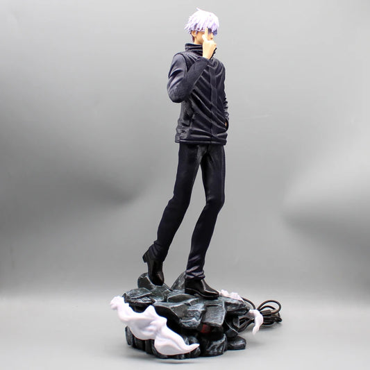 Figurine Gojo Satoru en tenue noire, debout sur socle rocheux avec câble électrique.